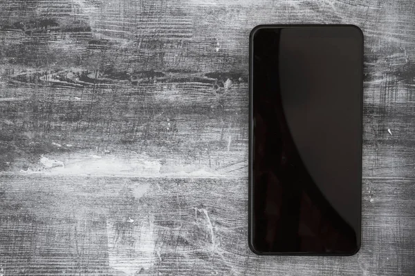 Порожній екран чорний мобільний телефон на вивітрюваному чорному гранжевому дереві — стокове фото