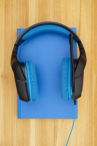 Auriculares azules y negros con micrófono y libro —  Fotos de Stock