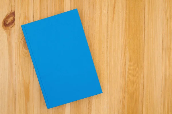 松木书桌上的蓝皮精装书 上面有供你学校使用的复制空间 或阅读或模仿 — 图库照片