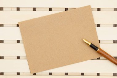 Mesajınız için boş kahverengi tebrik kartı ve tahta tahtada bir kalem.