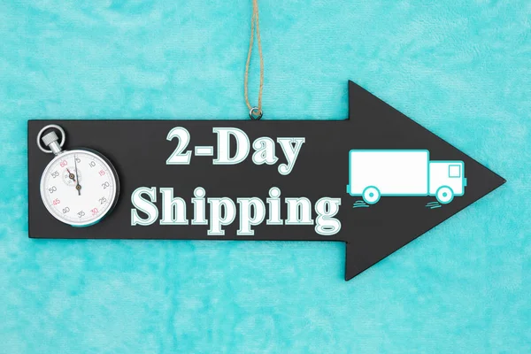蓝色毛绒材料上挂有秒表的箭头黑板标志上2天的航运类型消息 图库图片
