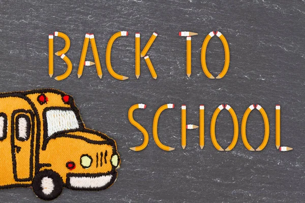 用铅笔和旧的黑色黑板上的校车返回学校留言 — 图库照片