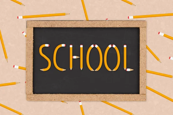 用铅笔和纸把铅笔写在黑板上的学校字母组合在一起 — 图库照片