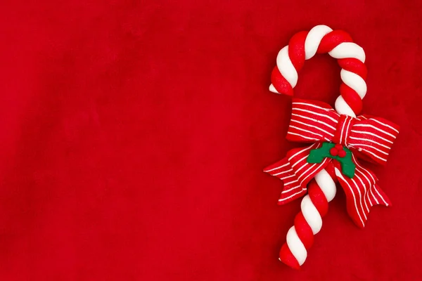 赤いぬいぐるみの材料と休日やクリスマスのメッセージのためのコピースペースと弓とキャンディー杖を持つクリスマスの背景 — ストック写真