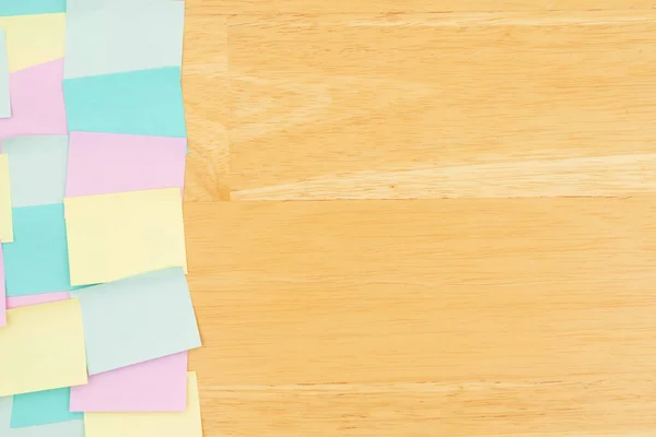 Sticky note background with multi-color notes on a wood desk wood with copy space for your office or reminder message