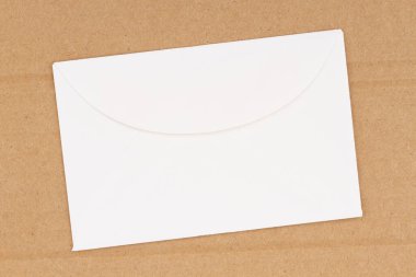 İleti için kopya alanı olan kahverengi desenli karton zemin üzerindeki boş beyaz zarf