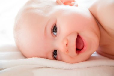 Tatlı küçük çocuk dostu tutum ile beyaz güneşli yatak odasında oynamak. Yakın çekim güzel bir uyku bebek çocuk portresi. Yeni doğan, çocukluk tema. Tekstil ve çocuklar için yatak. Aile sabah evde. Oyuncak ayı ile mide süre içinde yeni doğmuş çocuk.