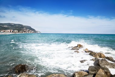 Denizin kenarında çakıl taşları. İpeksi mavi denizin dalgaları. Yaz plaj arka plan. Liguria, İtalya.