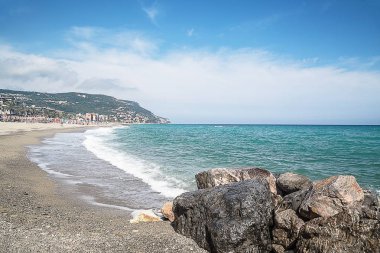 Denizin kenarında çakıl taşları. İpeksi mavi denizin dalgaları. Yaz plaj arka plan. Liguria, İtalya.