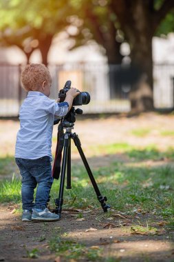 Küçük çocuk parkta tripod üzerinde kamera fotoğraf çekimi
