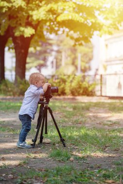 Küçük çocuk parkta tripod üzerinde kamera fotoğraf çekimi