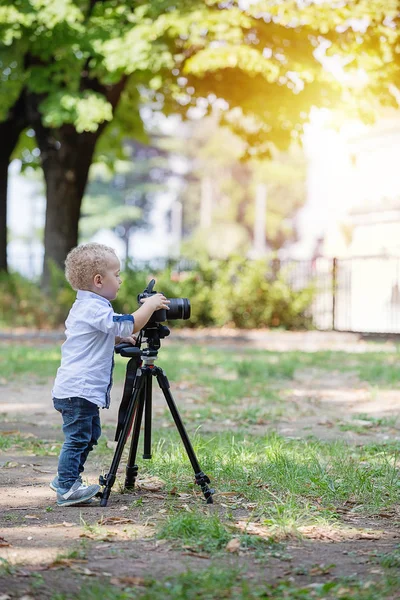 Malý chlapec fotografování na fotoaparátu na stativu v parku — Stock fotografie