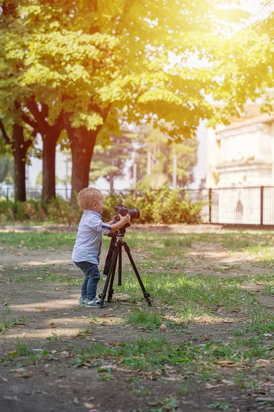 Malý chlapec fotografování na fotoaparátu na stativu v parku — Stock fotografie