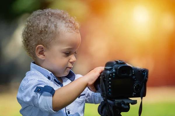 Kleiner Junge fotografiert mit der Kamera auf Stativ im Park — Stockfoto