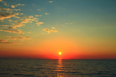 Sarı güneşin altında deniz yüzeyi ile parlak günbatımı