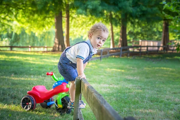 Usmívající se blond kudrnaté dítě hraje s kole — Stock fotografie