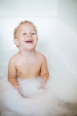 Closeup iki yaşındaki bir çocuğa banyo küvet içinde tarafından köpük ile eğlenmek. Saflık ve hijyen eğitimi sembolü.