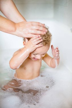 Closeup iki yaşındaki bir çocuğa banyo küvet içinde tarafından köpük ile eğlenmek. Saflık ve hijyen eğitimi sembolü.