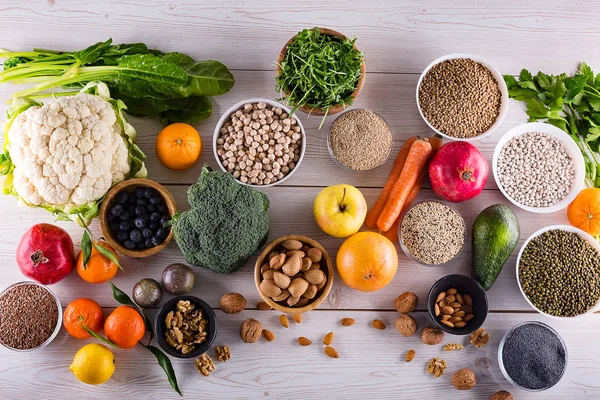 Healthy food clean eating : fruit, vegetable, seeds, superfood, cereals, leaf vegetable on black wood background with copy space, top view.