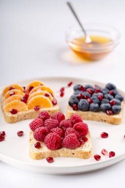 Nar taneleri, bal ve beyaz arka plan üzerinde meyveleri ile sandviç. Çiğ gıda. Kahvaltı ve öğle yemeği için sağlıklı yemek. Seçici odak.