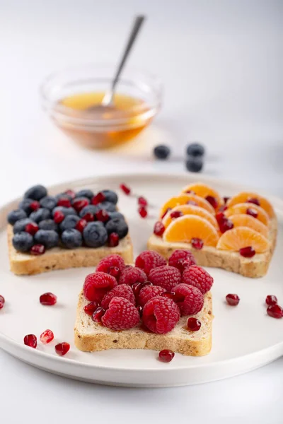 Sandwich with pomegranate grains, honey and berries over white background. Raw food. Healthy food for breakfast or lunch. Selective focus.