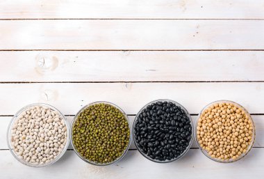 Ham mung fasulye, fasulye, fasulye ve soya fasulyesi cam kase Beyaz ahşap zemin üst görünümünde, metin için yer. Vegan protein kaynağı. Superfoods ve temiz sağlıklı yemek. 