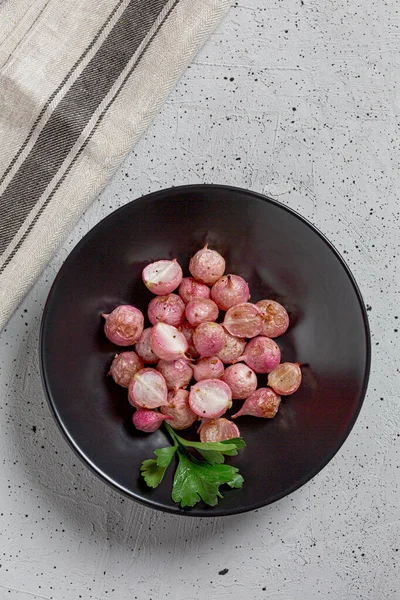 Όμορφα καβουρδισμένα ραπανάκια σε μαύρο πιάτο σε ροζ τραπέζι από κοντά. — Φωτογραφία Αρχείου