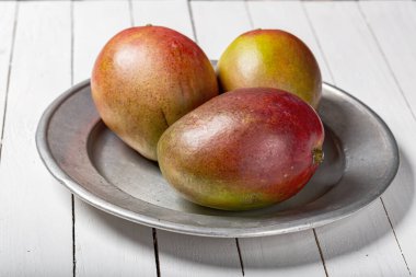 Beyaz ahşap masada taze mango meyvesi.