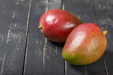 Siyah ahşap masada taze mango meyvesi..