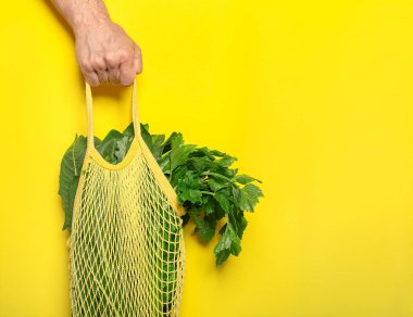 Bir gönüllü, sarı arka planda bir çantanın içinde yiyecek saklar.