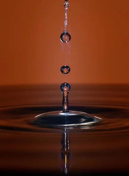 Gotas de água caem na água — Fotografia de Stock
