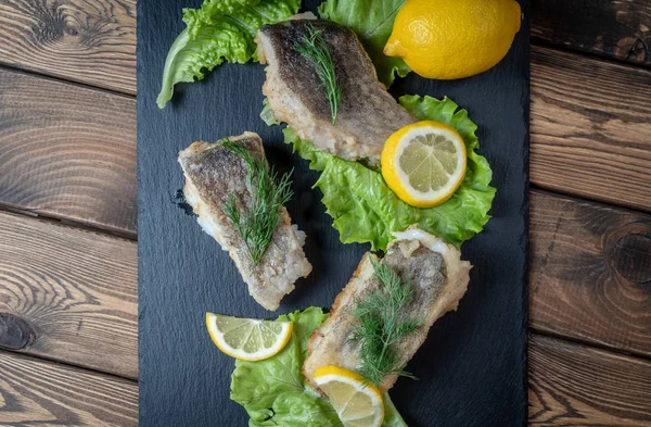 Fried fish with lemon and lettuce leaves — Stock Photo, Image