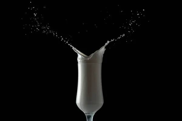 Молочный коктейль брызгает из стакана. Изолированное изображение на черном фоне . — стоковое фото