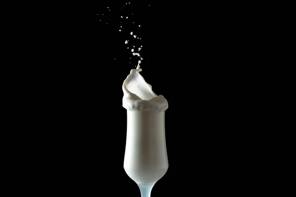 Молоко струшує бризки зі склянки. Ізольоване зображення на чорному тлі . — стокове фото