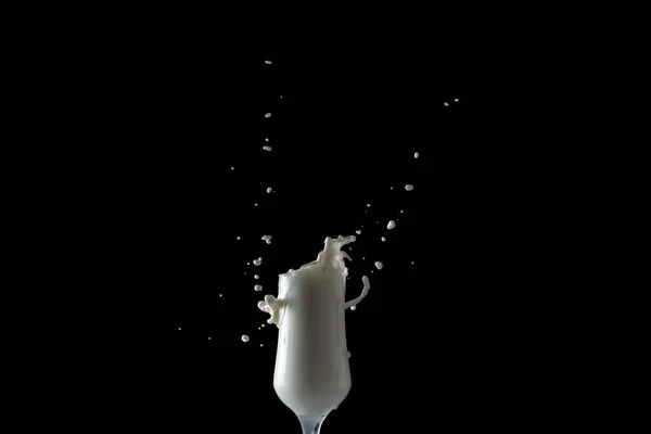 Молочный коктейль брызгает из стакана. Изолированное изображение на черном фоне . — стоковое фото