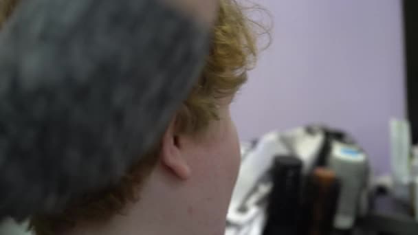 Un joven corta el pelo en una peluquería. De cerca. — Vídeos de Stock
