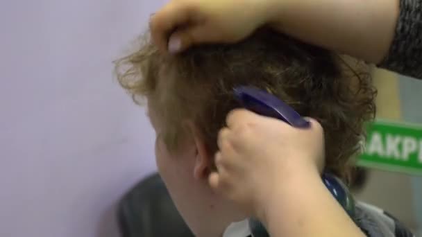 A young man cuts hair in a barber shop. Close up — Stock Video