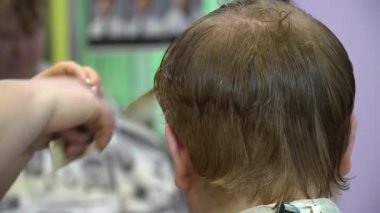 Genç bir adam berber dükkanında saç keser. Yakın çekim