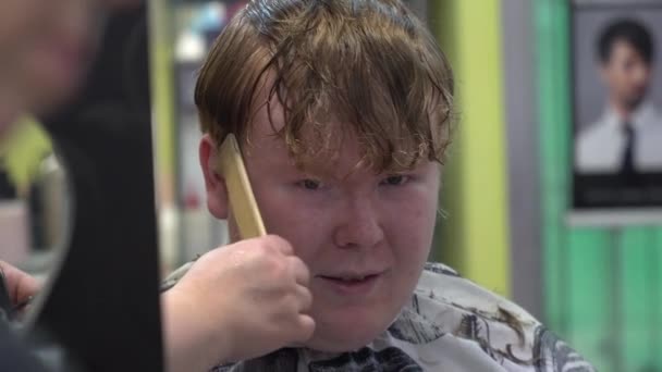 Um jovem corta cabelo numa barbearia. Fechar — Vídeo de Stock