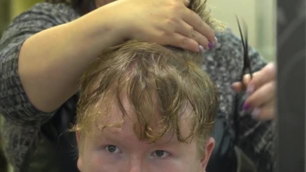 Een jonge man snijdt haar in een kapperszaak. Close-up — Stockvideo