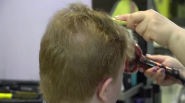 Genç bir adam berber dükkanında saç keser. Yakın çekim