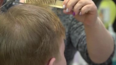 Genç bir adam berber dükkanında saç keser. Yakın çekim