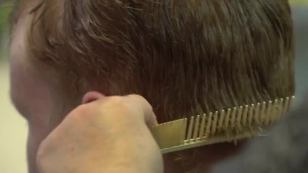 Ein junger Mann schneidet in einem Friseursalon Haare. Nahaufnahme — Stockvideo