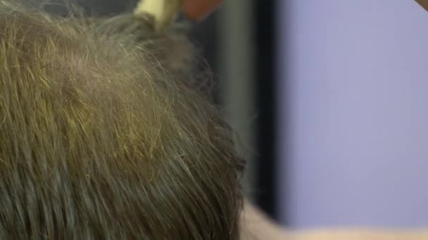 Молодий чоловік вирізає волосся в перукарні. крупним планом — стокове відео