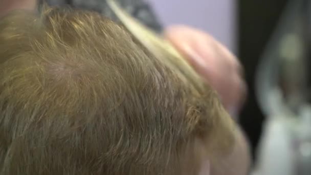 En ung man klipper håret i en frisörsalong. Närbild — Stockvideo