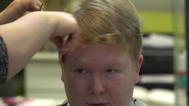 A young man cuts hair in a barber shop. Close up — Stock Video