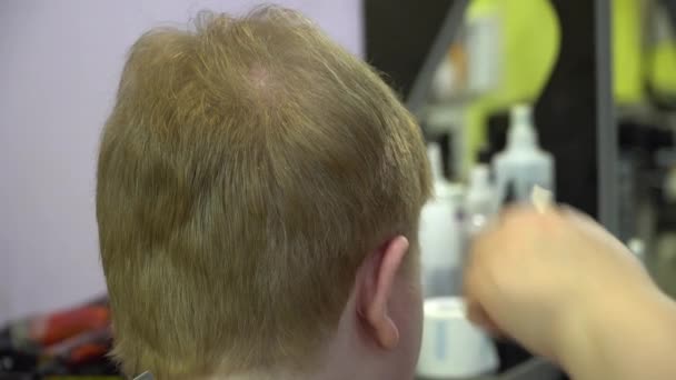 Молодий чоловік вирізає волосся в перукарні. крупним планом — стокове відео