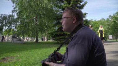 Genç adam parkta fotoğraf çekiyor.