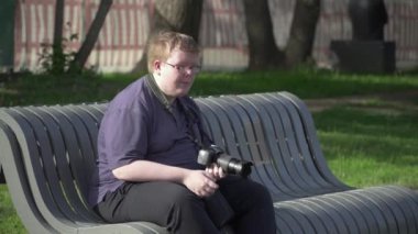 Genç adam parkta fotoğraf çekiyor.