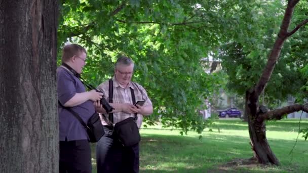 Молодий чоловік фотографує в парку — стокове відео